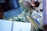 A workspace featuring art supplies, including colored pencils, a sketchbook, an iPad in a case, and a palette of watercolor paints arranged on a table with a floral pattern. The setup suggests a creative atmosphere with tools for drawing and painting.