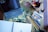 A workspace featuring art supplies, including colored pencils, a sketchbook, an iPad in a case, and a palette of watercolor paints arranged on a table with a floral pattern. The setup suggests a creative atmosphere with tools for drawing and painting.