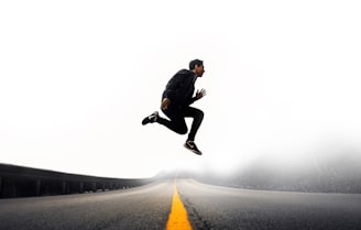 man jumping above gray and yellow concrete road at daytime