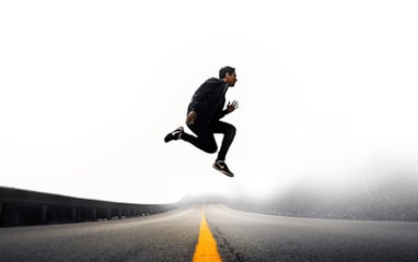 man jumping above gray and yellow concrete road at daytime