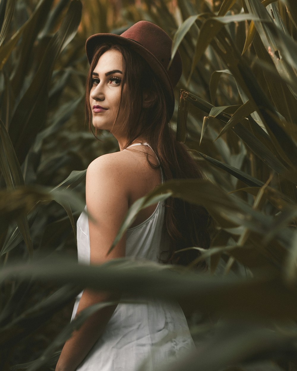 a woman wearing a hat standing in a field