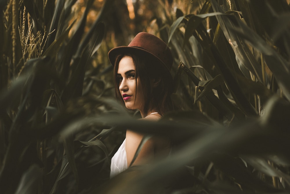 Mujer en camisa blanca con sombrero de pie en el campo de maíz