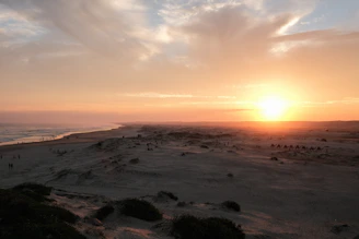 A candid shot of a family sharing a quiet moment on soft sand dunes at sunset, warm and cinematic.