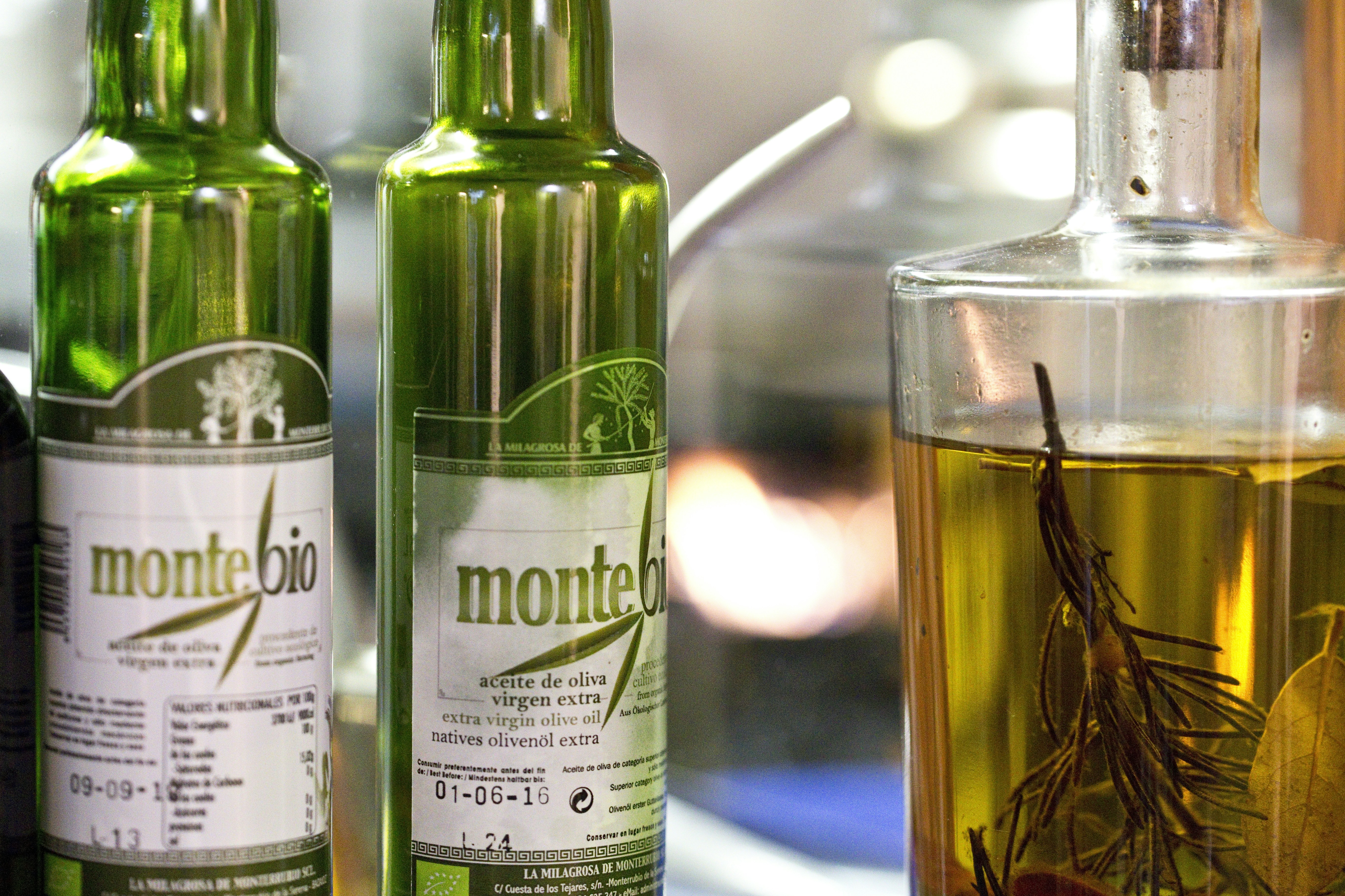 Green glass bottle of extra virgin olive oil with olive branch