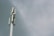 A tall telecommunications tower with several antenna panels and a cloudy sky background.