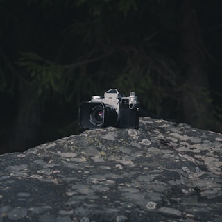 Close-up of a vintage camera resting on a textured dark surface with bronze highlights.