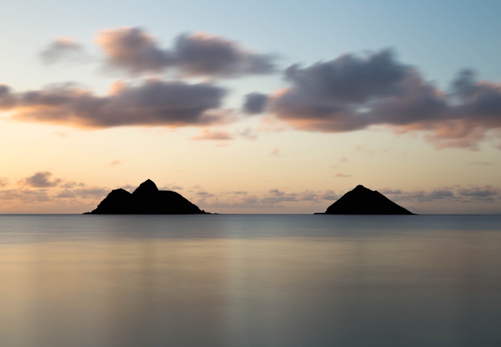 silhouette of two islands under cloudy sky