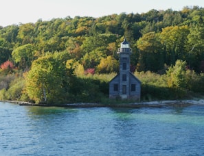 A cozy New England lighthouse framed by autumn leaves at sunset.