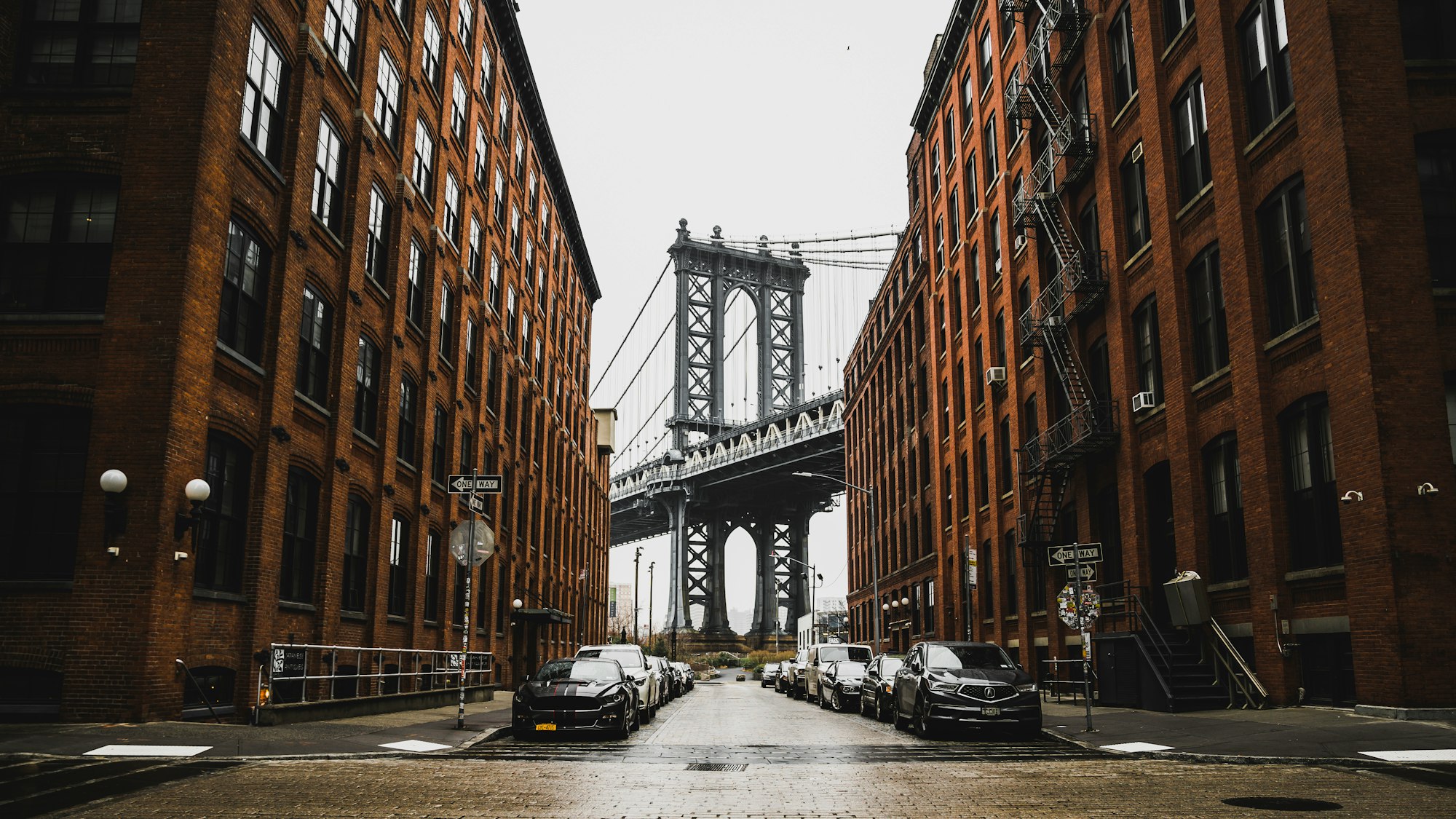A Brooklyn side street with a view of the Brooklyn Bridge between two brick buildings