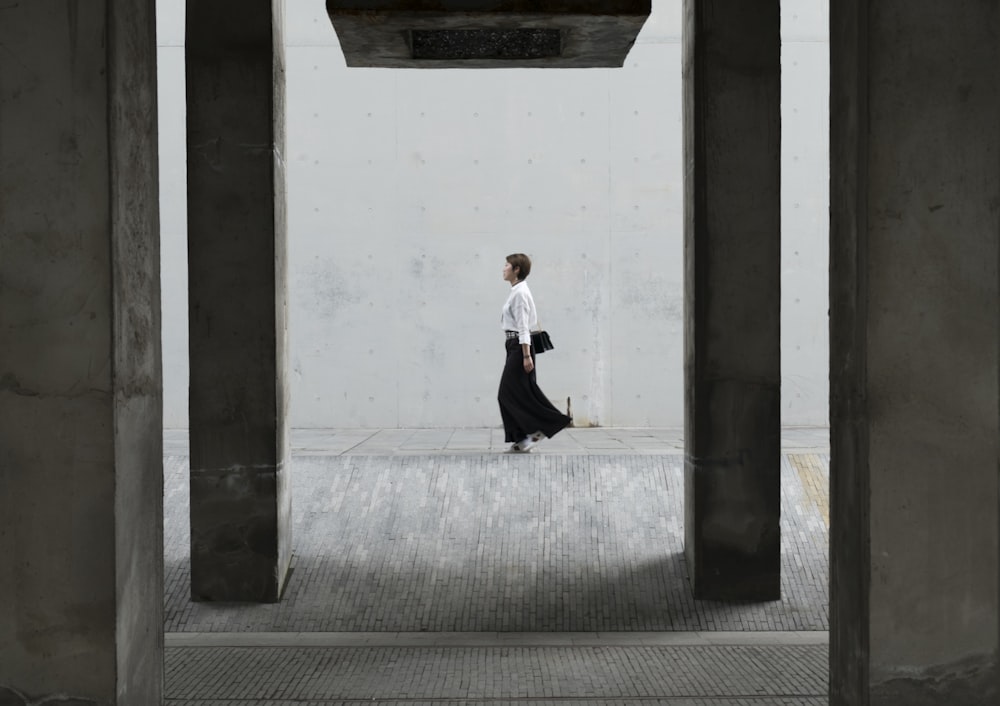 femme marchant sous un pont en béton pendant la journée