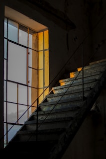 Sunlight filtering through large glass panels highlighting the precise craftsmanship of a modern staircase.
