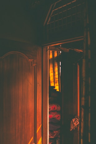 Warmly lit interior of mahohar cloth house showing wooden shelves filled with colorful cotton, silk, and linen fabrics.