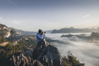 man on top of mountain taking pictures