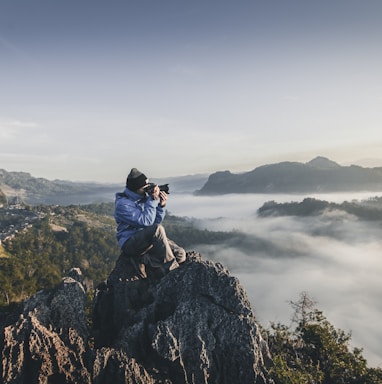 man on top of mountain taking pictures