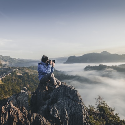 man on top of mountain taking pictures