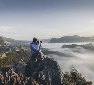 man on top of mountain taking pictures