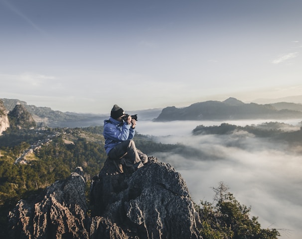 man on top of mountain taking pictures