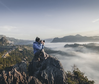 man on top of mountain taking pictures