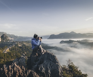 man on top of mountain taking pictures