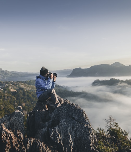 man on top of mountain taking pictures