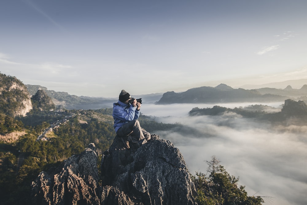 Mann auf dem Gipfel des Berges macht Fotos