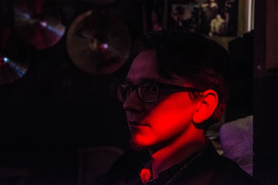 A crimson-lit album cover glowing softly on a dark background.