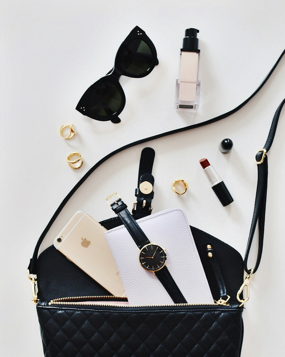gafas de sol de mujer y bolso negro con reloj y iPhone 6