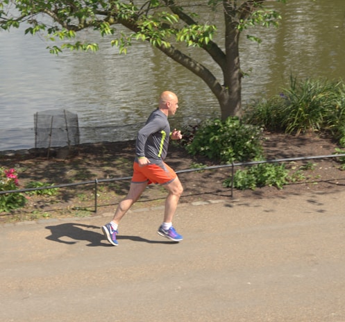 A man jogging outdoors in athletic wear during sunrise.