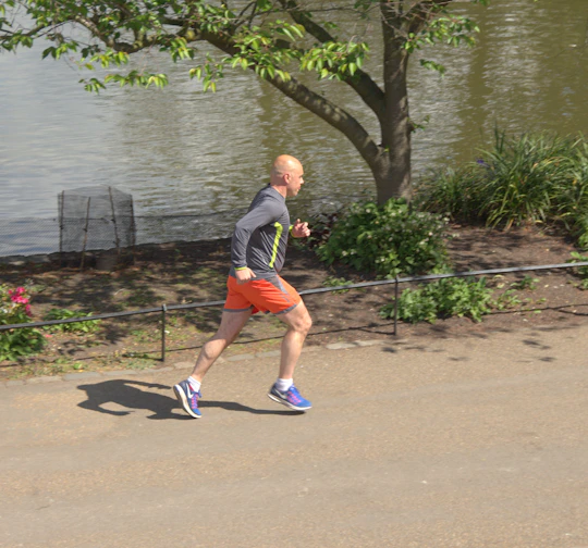 A stylish man wearing comfortable athleisure gear jogging in a city park at sunrise.
