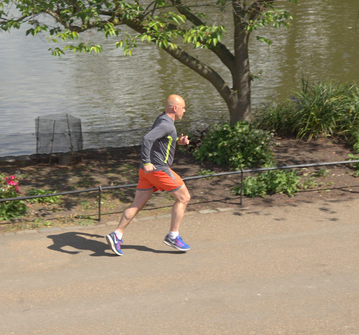 A man jogging in comfortable casual sportswear on a city street at sunrise