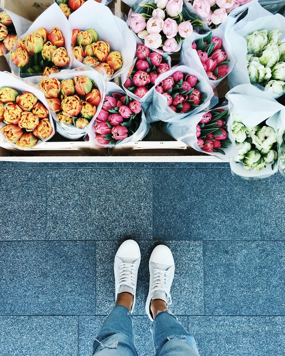 A person looking down at various flower bouquets.