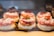 A display of pastries arranged neatly in rows, each topped with powdered sugar, cream, strawberries, and pastry crust. The desserts are placed in a well-lit setting with a warm and inviting atmosphere.