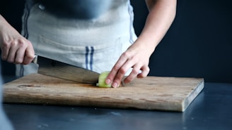 person slicing green vegetable on chopping board