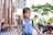 Young woman happily showing her anime-themed backpack in a vibrant urban setting.