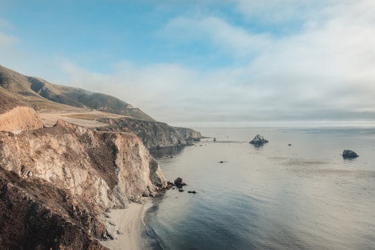 gray and brown cliff near the ocean in Bixby Creek Arch Bridge United States