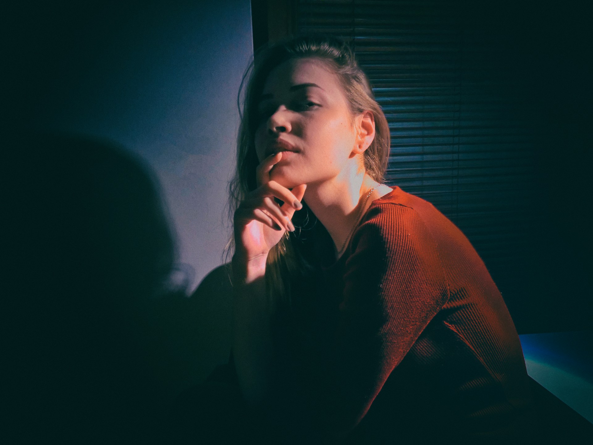 A playful pose in a cozy, dimly lit room, showcasing a teasing smile and inviting eyes.