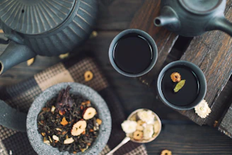Rustic basket filled with wildcrafted yaupon leaves beside a steaming cup of tea.