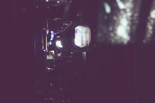 A dimly lit vintage film projector casting light onto a dark cinema wall.