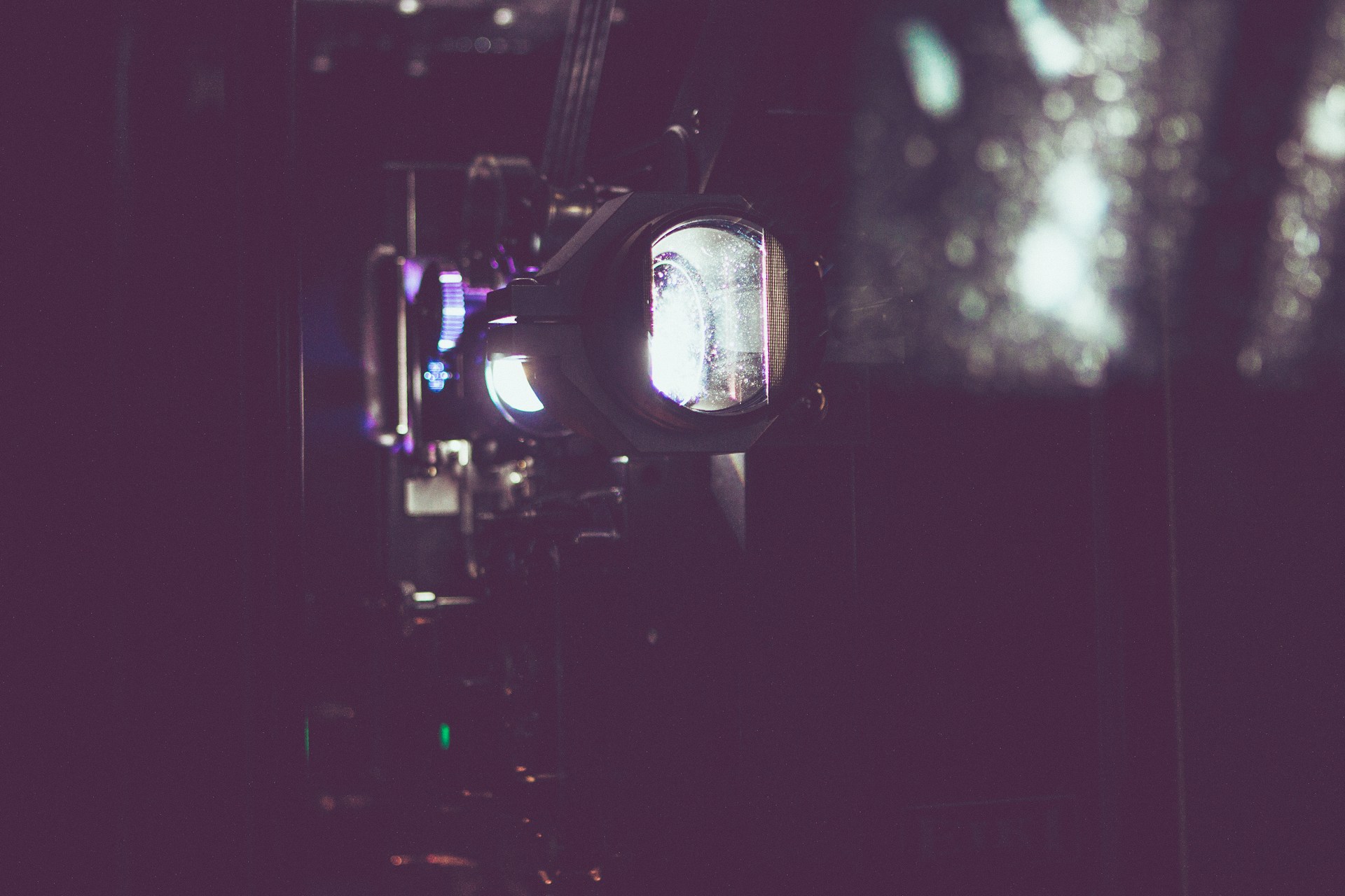 A close-up of an antique film projector casting flickering shadows on a wall, evoking a sense of nostalgia.
