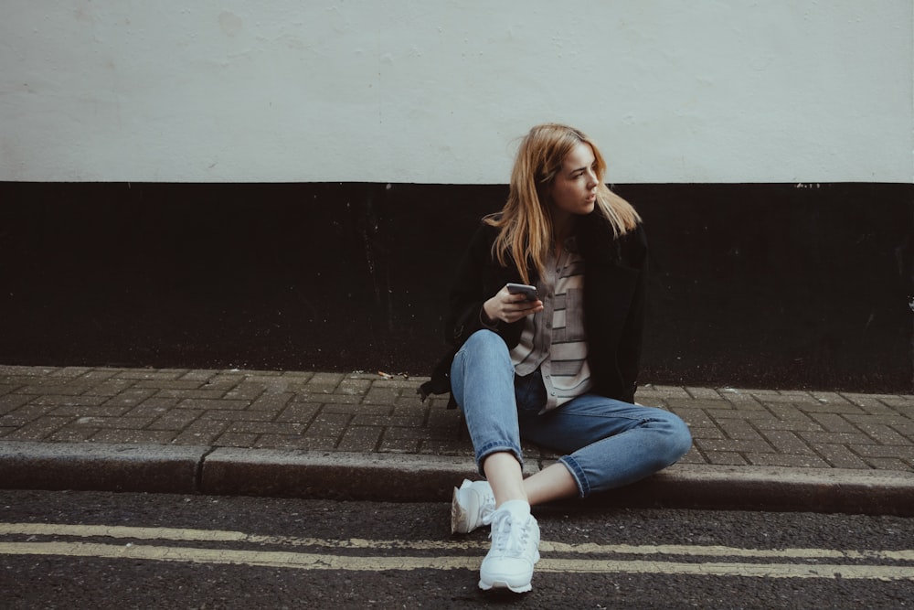 woman sitting on floor while holding smartphone