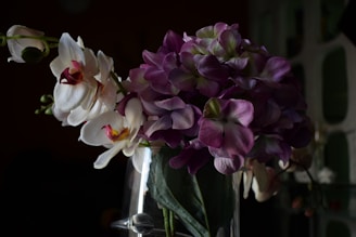 Delicate white and purple orchids displayed in a modern glass container.