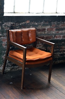 A rustic wooden chair lovingly restored with a patchwork cushion, set against a backdrop of reclaimed wood walls.