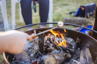 Close-up of hands roasting marshmallows on a campfire, glowing in the night.