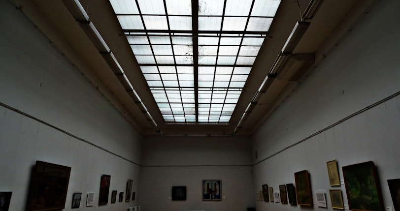 A bright, airy gallery space with contemporary paintings hanging on white walls.