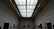 A serene gallery room with white walls showcasing rows of AI-generated art pieces.
