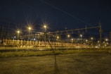 Nighttime shot of a rail yard illuminated with safety lights and active machinery.