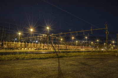 Nighttime shot of a rail yard illuminated with safety lights and active machinery.