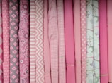 Rolls of printed fabric in soft pastel colors for children's clothing.
