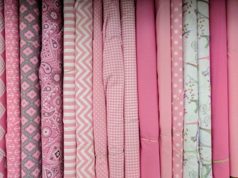 Rolls of printed fabric in soft pastel colors for children's clothing.