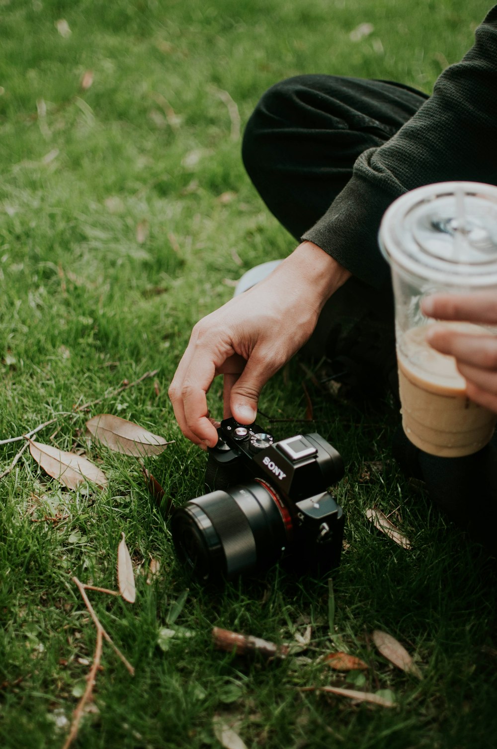 persona usando una cámara Sony SLR negra en un campo de hierba verde